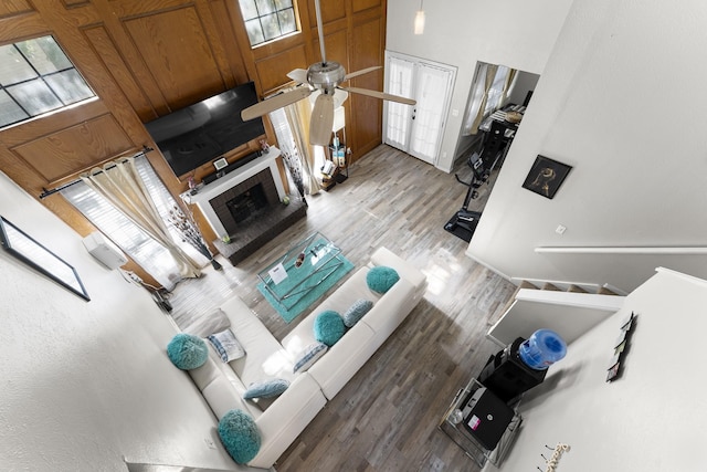 living room with a high ceiling, a fireplace, ceiling fan, and hardwood / wood-style floors