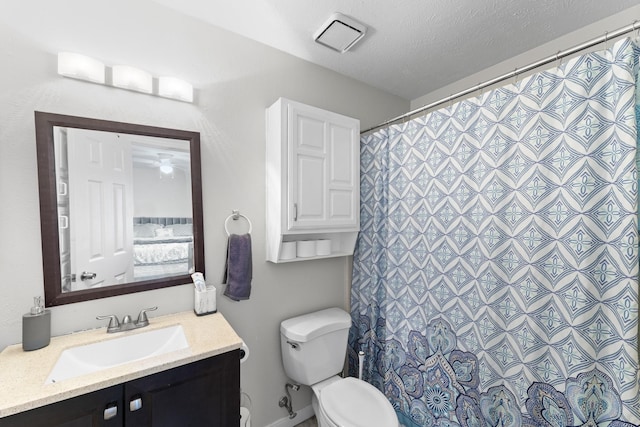 bathroom with a textured ceiling, vanity, and toilet