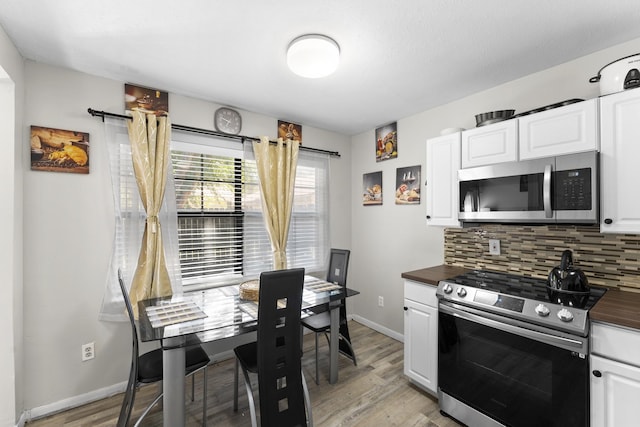 kitchen with stainless steel appliances, white cabinetry, tasteful backsplash, and light hardwood / wood-style flooring