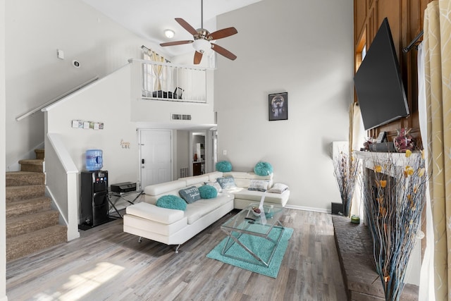 living room with a high ceiling, ceiling fan, and hardwood / wood-style flooring