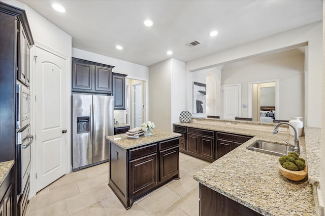 kitchen featuring a kitchen island, stainless steel appliances, sink, kitchen peninsula, and light stone counters