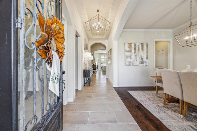 foyer with wood-type flooring, ornamental molding, and a chandelier