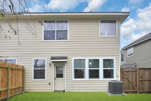 rear view of property with cooling unit and a lawn