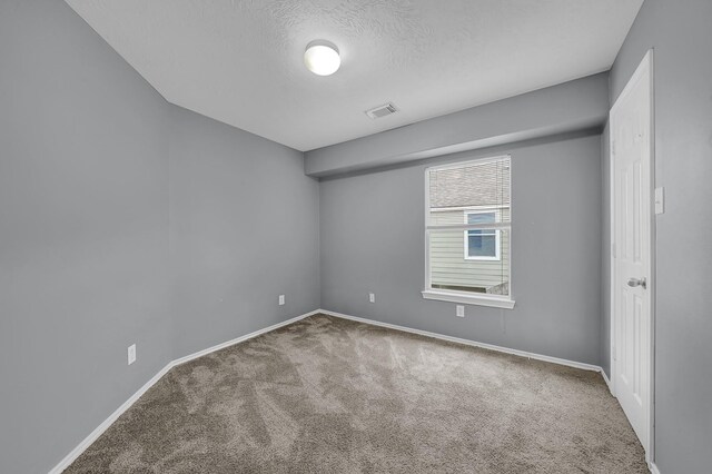 unfurnished room with carpet flooring and a textured ceiling