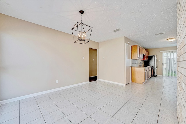 kitchen with a textured ceiling, a chandelier, decorative light fixtures, light tile patterned floors, and decorative backsplash