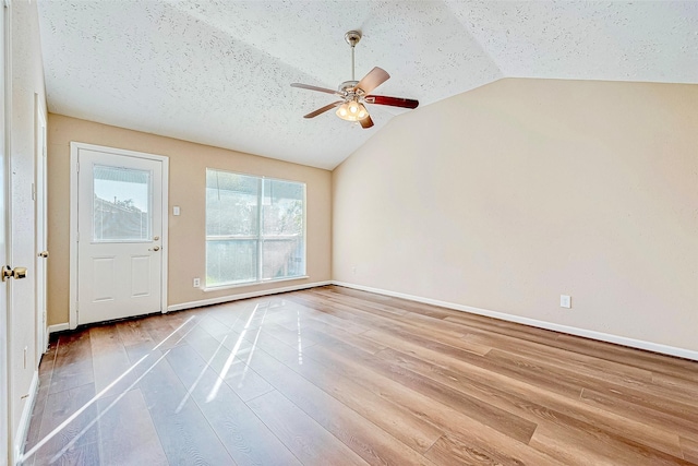 empty room featuring ceiling fan, a textured ceiling, light wood-type flooring, and vaulted ceiling