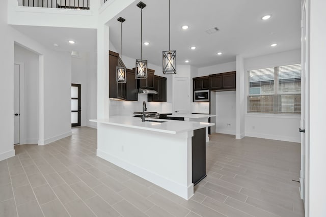 30551 Zoysia Point Ln, Fulshear, TX 77423 - kitchen with stainless steel microwave, light countertops, dark brown cabinets, under cabinet range hood, and recessed lighting