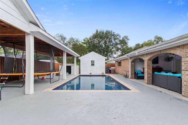 view of swimming pool with a patio area, a storage unit, an outdoor living space, and a trampoline