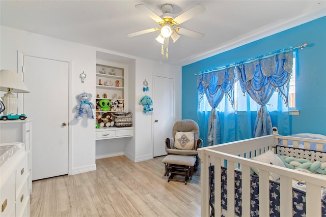 bedroom featuring ceiling fan, a crib, and light hardwood / wood-style flooring