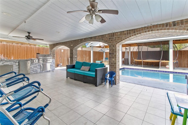 view of patio / terrace featuring ceiling fan, area for grilling, a fenced in pool, and an outdoor kitchen