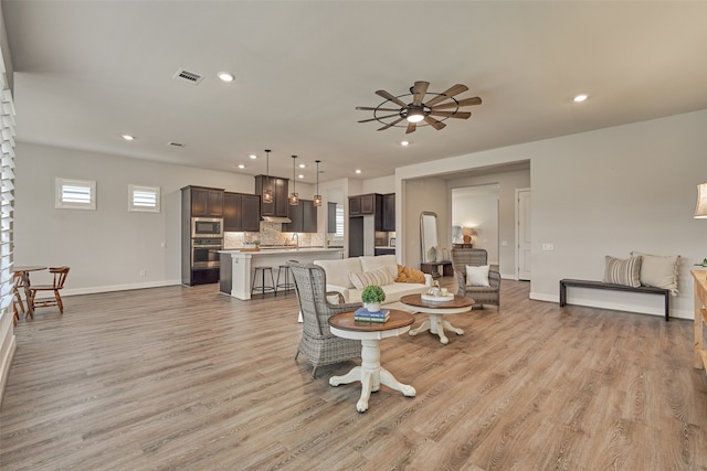 dining room featuring sink, ceiling fan, and light wood-type flooring