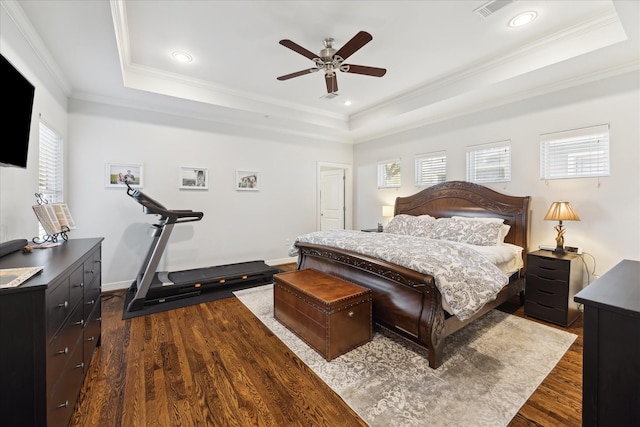 bedroom featuring ceiling fan, dark wood-type flooring, and a tray ceiling