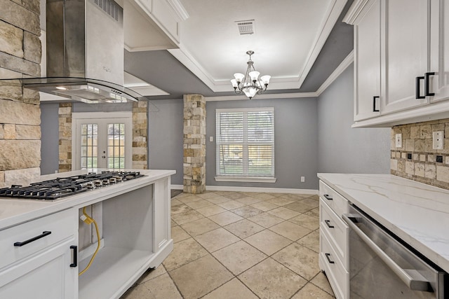 kitchen featuring a raised ceiling, appliances with stainless steel finishes, a healthy amount of sunlight, white cabinets, and exhaust hood