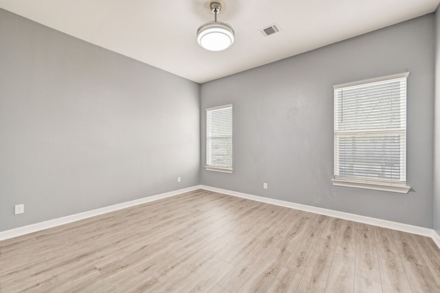 empty room with light hardwood / wood-style floors and plenty of natural light