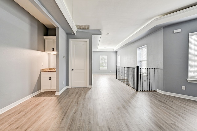 unfurnished room with a raised ceiling and light hardwood / wood-style floors