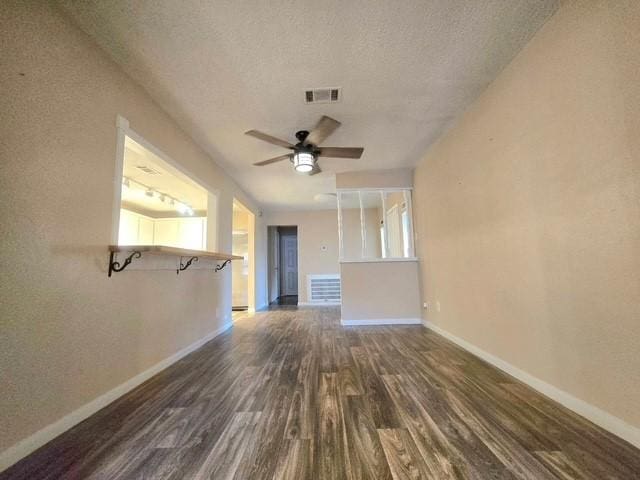 unfurnished living room featuring dark hardwood / wood-style flooring, a textured ceiling, and ceiling fan