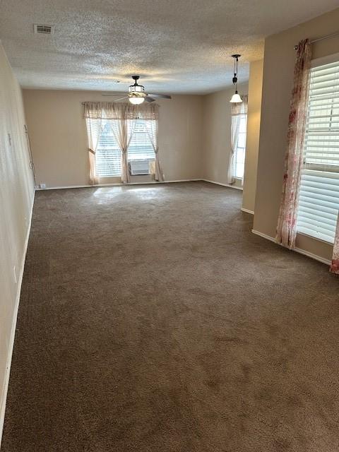 carpeted empty room featuring a textured ceiling, ceiling fan, and a wealth of natural light