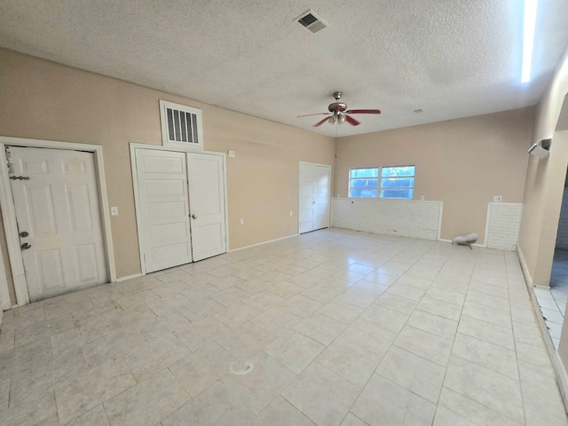 interior space with a textured ceiling, two closets, ceiling fan, and light tile patterned floors