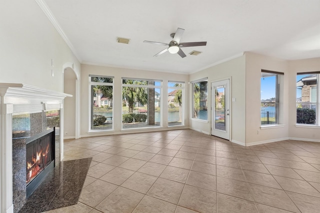 unfurnished living room featuring a high end fireplace, ceiling fan, light tile patterned floors, and plenty of natural light