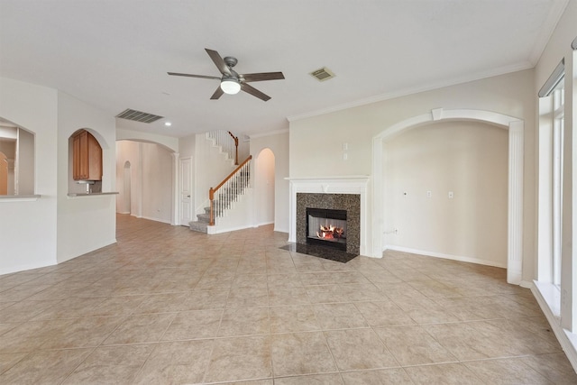 unfurnished living room with ceiling fan, ornamental molding, a fireplace, and light tile patterned floors