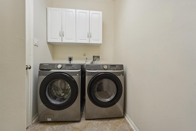 clothes washing area with washer and dryer, light tile patterned floors, and cabinets