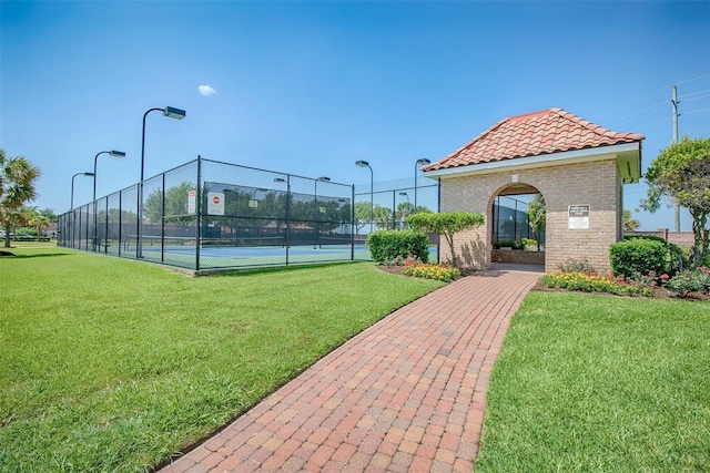 view of tennis court featuring a yard