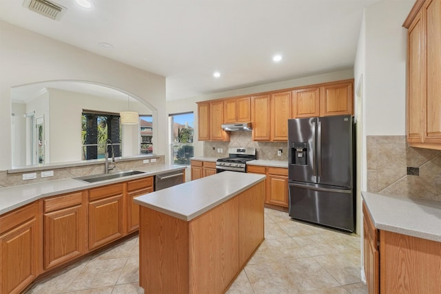 kitchen featuring light tile patterned floors, a kitchen island, backsplash, appliances with stainless steel finishes, and sink