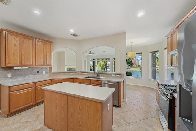 kitchen featuring stainless steel appliances, sink, decorative light fixtures, a center island, and kitchen peninsula