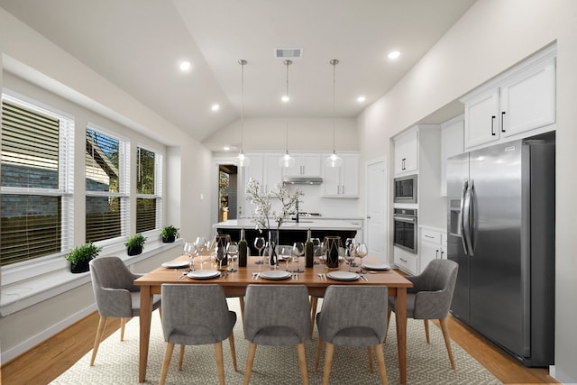 dining area with high vaulted ceiling and light wood-type flooring