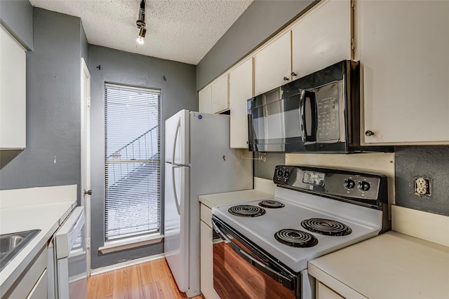 kitchen with white appliances, rail lighting, a textured ceiling, white cabinets, and light hardwood / wood-style flooring