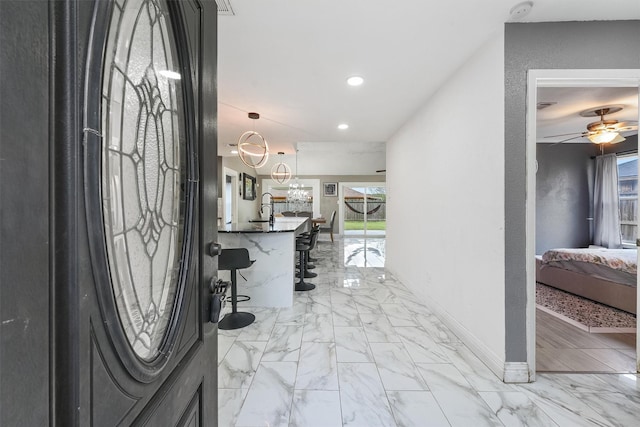 entryway with sink and ceiling fan with notable chandelier