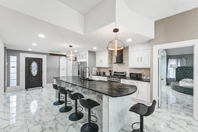 kitchen featuring a kitchen bar, white cabinetry, appliances with stainless steel finishes, and hanging light fixtures