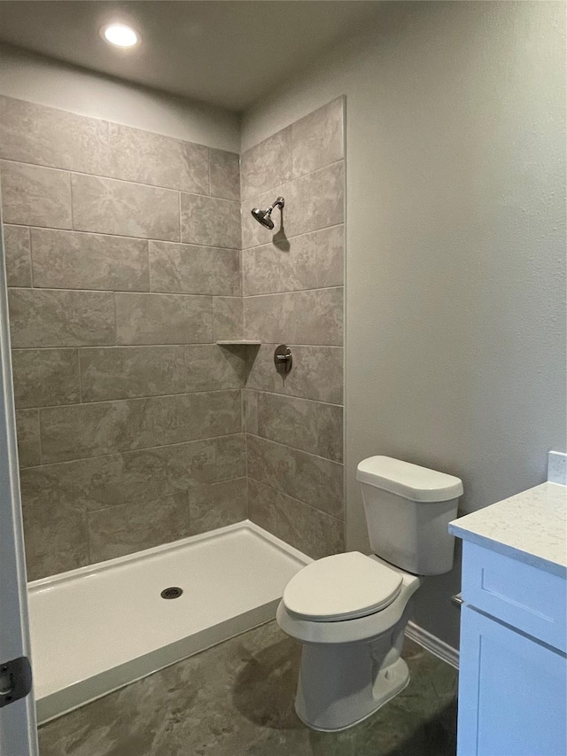 bathroom featuring a tile shower, vanity, and toilet