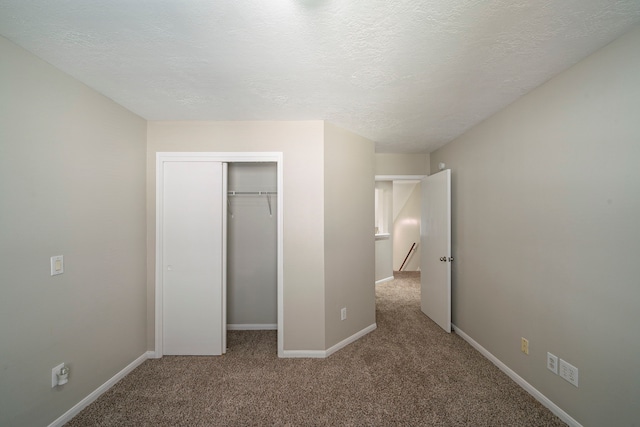 unfurnished bedroom with carpet, a closet, and a textured ceiling