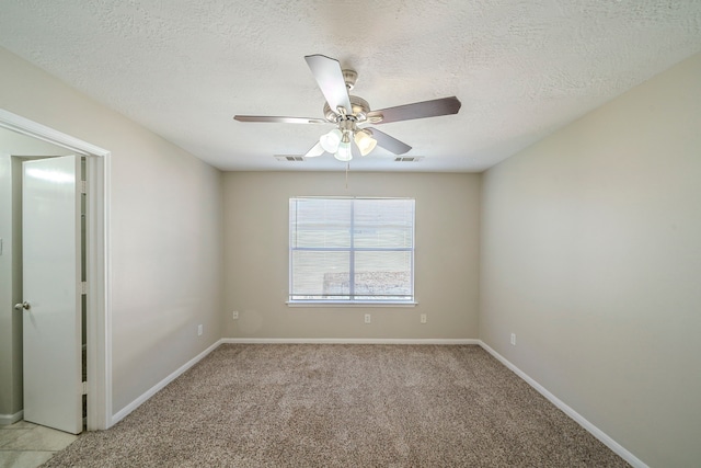 spare room featuring ceiling fan, light colored carpet, and a textured ceiling