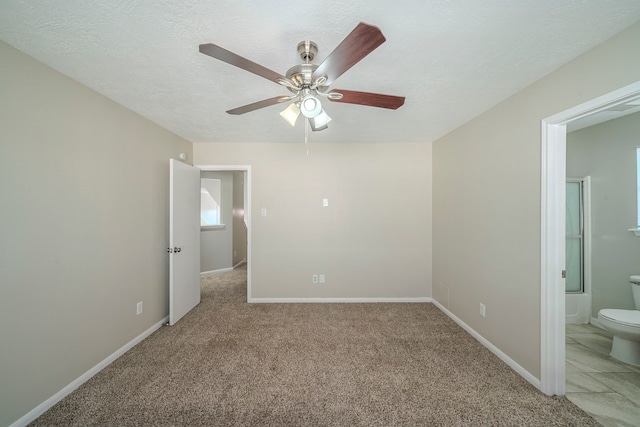 unfurnished bedroom with ensuite bathroom, light colored carpet, ceiling fan, and a textured ceiling