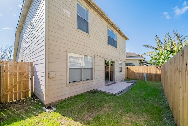 back of house with a yard and a patio