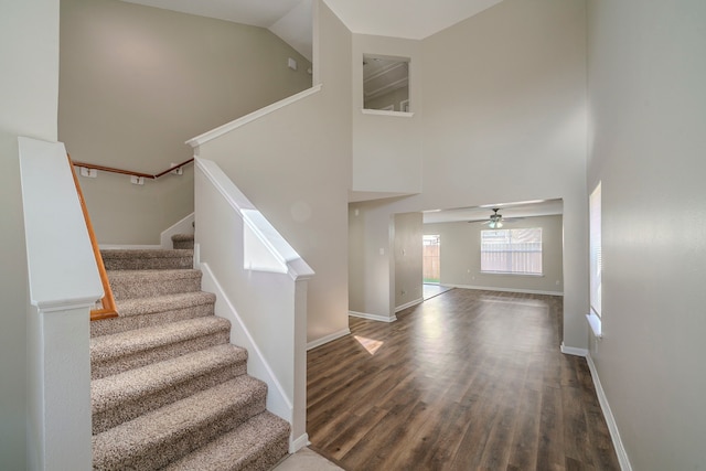 stairway featuring ceiling fan, hardwood / wood-style flooring, and a towering ceiling