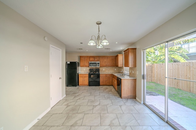 kitchen featuring black appliances, decorative backsplash, sink, hanging light fixtures, and a notable chandelier