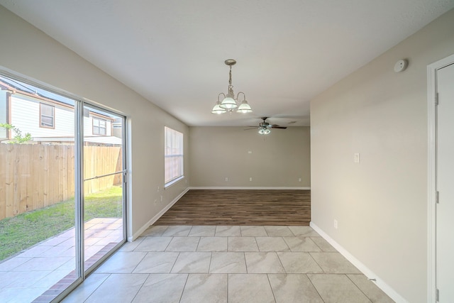 unfurnished dining area featuring ceiling fan with notable chandelier and light tile patterned flooring