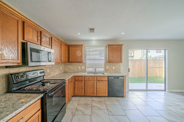 kitchen featuring backsplash, light tile patterned flooring, black appliances, light stone counters, and sink