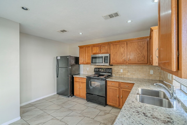 kitchen with backsplash, black appliances, sink, light tile patterned flooring, and light stone countertops