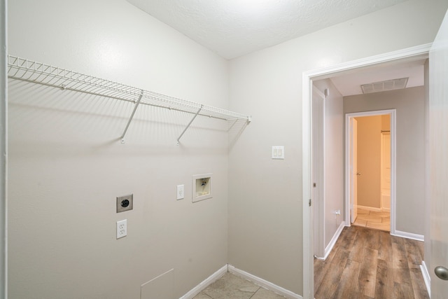 laundry room with a textured ceiling, hardwood / wood-style flooring, hookup for a washing machine, and hookup for an electric dryer