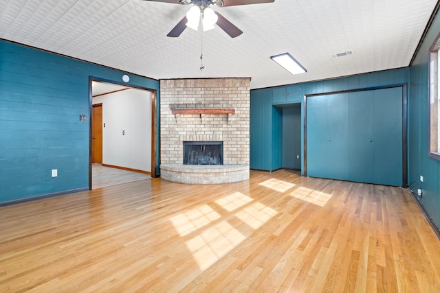 unfurnished living room featuring ceiling fan, a fireplace, and wood-type flooring