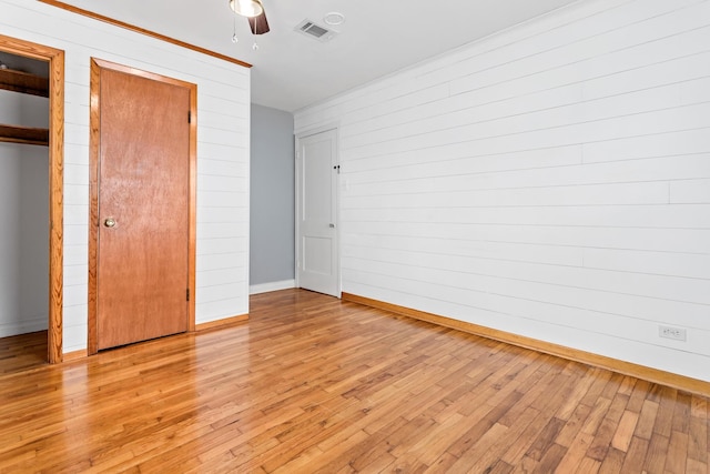 unfurnished bedroom featuring multiple closets, ceiling fan, and light hardwood / wood-style floors