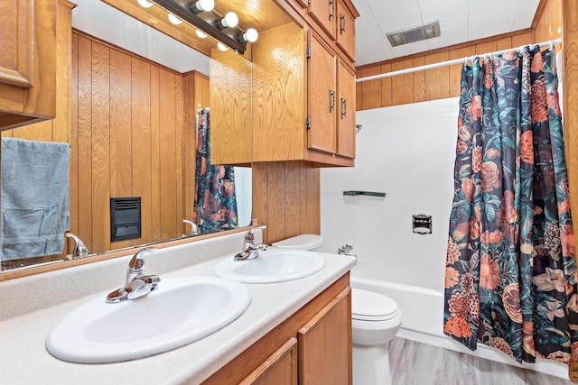 full bathroom with wooden walls, hardwood / wood-style floors, toilet, shower / bath combination with curtain, and vanity