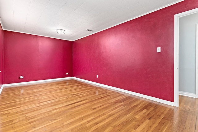 spare room with hardwood / wood-style flooring and crown molding