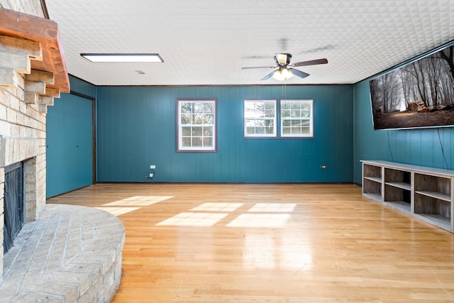 unfurnished living room featuring a fireplace, ceiling fan, and light hardwood / wood-style flooring