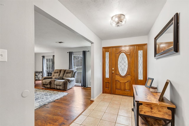 entryway with light tile patterned flooring and a textured ceiling