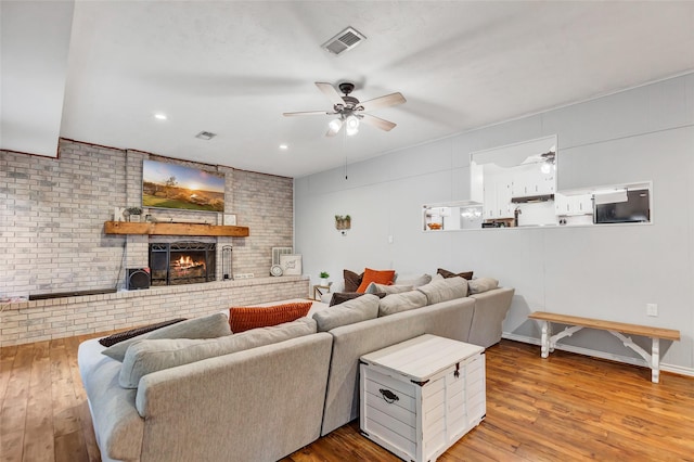 living room with a fireplace, brick wall, and hardwood / wood-style floors